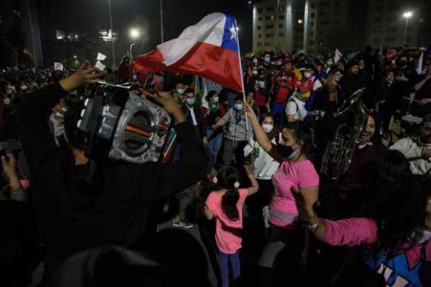 Decenas de personas celebran luego de conocer los resultados del plebiscito constitucional en Santiago (Chile). 