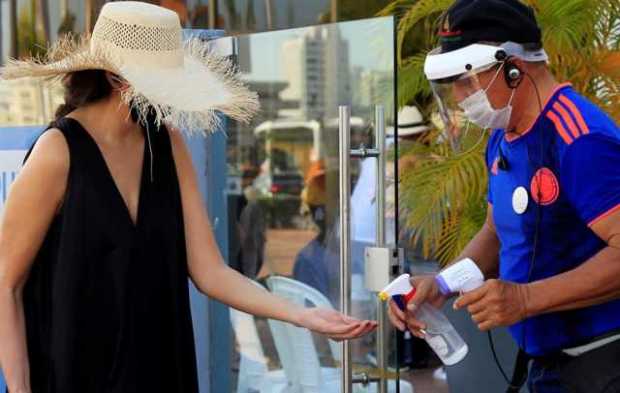 Una turista recibe alcohol para desinfectarse las manos antes de abordar una lancha hoy, en Cartagena. 