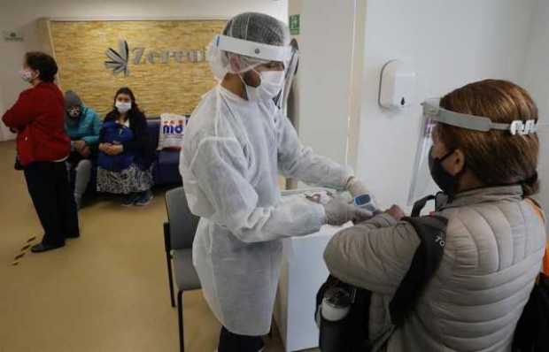 Enfermero toma la temperatura de una paciente que ingresa a la clínica Zerenia en Bogotá.