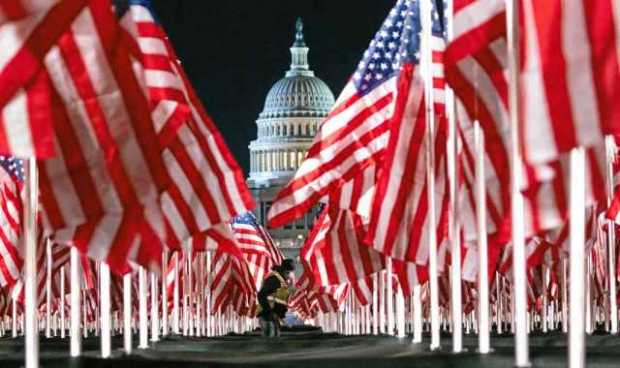 Una persona pasa entre las 200 mil banderas instaladas frente al Capitolio para la investidura de Biden. Las banderas representa