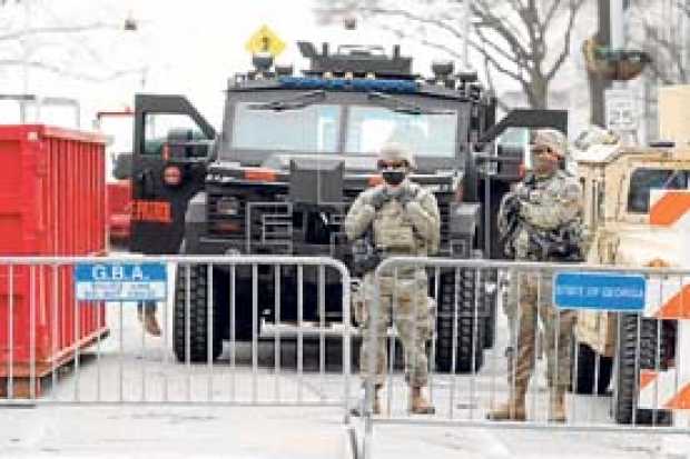 Tropas de la Patrulla Estatal de Georgia y miembros de la Guardia Nacional vigilan el edificio del Capitolio de Georgia, previas