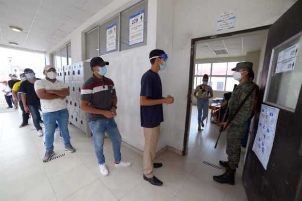 Ciudadanos esperan en fila para votar hoy, en un centro electoral en Guayaquil (Ecuador).