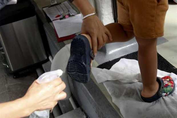 Una profesora le desinfecta la suela de los zapatos a un niño, en el Centro Educativo Hola Bebé en Medellín. 