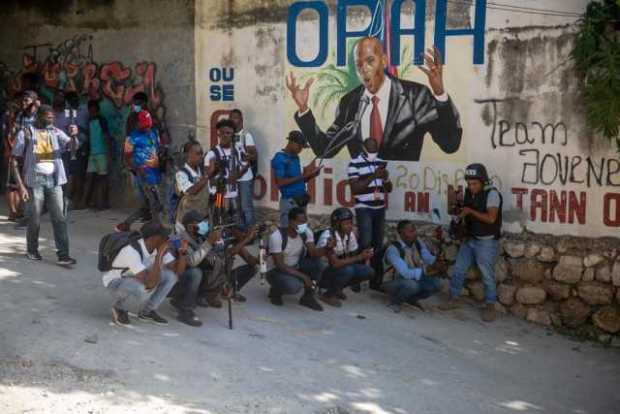 Un grupo de personas se reúnen en la calle junto a un mural del asesinado presidente Jovenel Moise hoy, en Puerto Príncipe (Hait