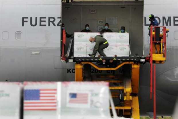 Integrantes de la Fuerza Aérea de Colombia desembarcan un cargamento de vacunas que llegaron desde Estados Unidos hoy a Bogotá