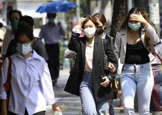 Varias mujeres caminan con mascarilla por una calle de Bangkok. Varias mujeres caminan con mascarilla por una calle de Bangkok.