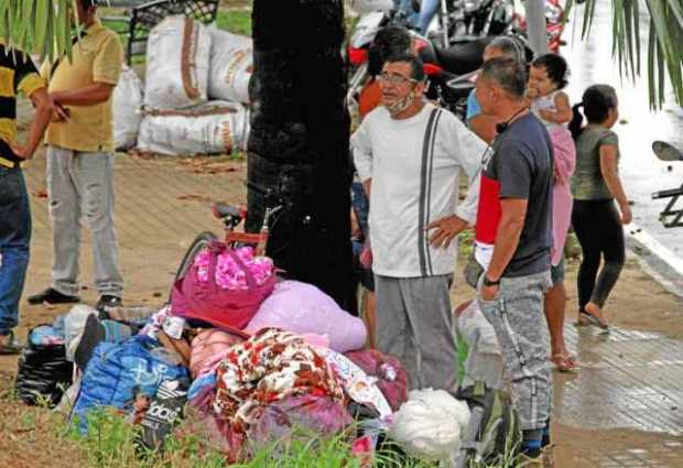 Migrantes venezolanos esperan con sus pertenencias tras cruzar en botes desde La Victoria, en Venezuela, hasta Arauquita, en Col