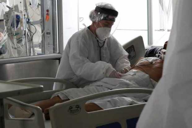 Una empleada de la salud atiende a un paciente en una unidad de cuidados intensivos para enfermos de covid-19.