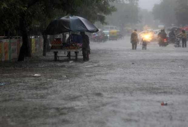 Los automovilistas indios pasan en una calle inundada durante las fuertes lluvias después de que el ciclón Tauktae azotara Ahmed
