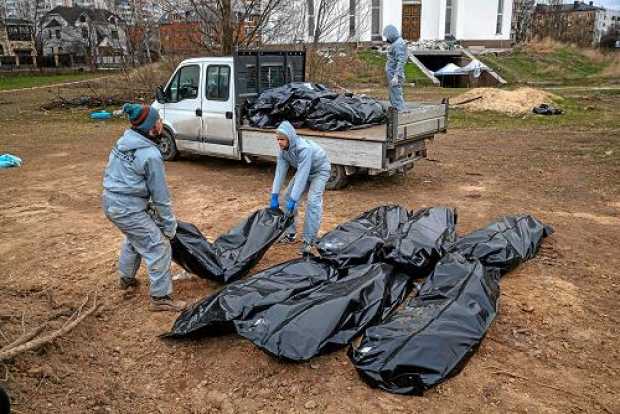 Autoridades forenses recogen cadáveres envueltos en plásticos para su traslado a la morgue en Bucha (Ucrania). 