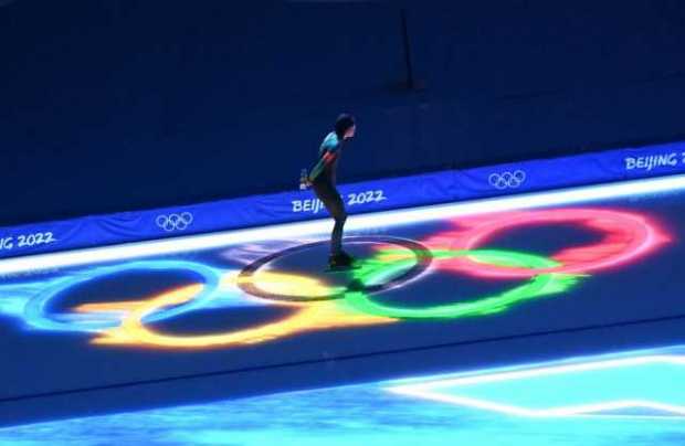 Una patinadora pasa frente a los Aros Olímpicos en la pista previo al evento de 5.000m femenino de patinaje de velocidad de los 
