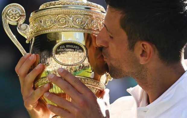 El serbio Novak Djokovic besa el trofeo después de ganar la final del torneo de Wimbledon ante el australiano Nick Kyrgios, hoy 