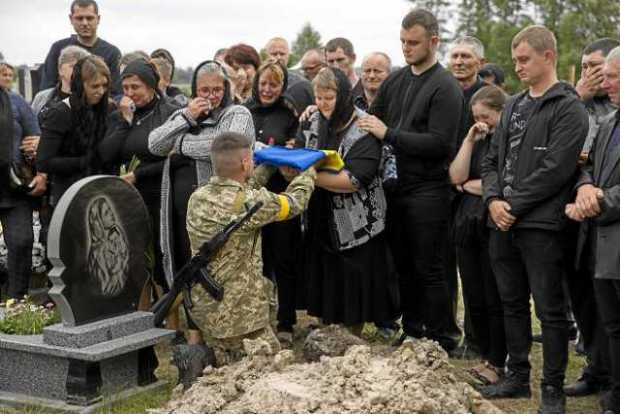 Un soldado entrega una bandera ucraniana a la madre del soldado de ese país, Volodimir Dmytras, durante sus honras fúnebres ayer