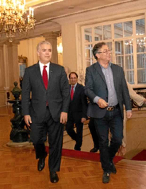 El presidente, Iván Duque, camina por un pasillo de la Casa de Nariño acompañado del presidente electo, Gustavo Petro.