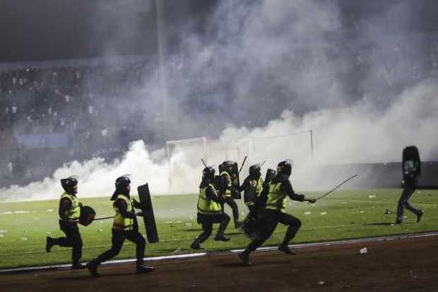 Los oficiales de policía corren mientras intentan evitar que los fanáticos del fútbol ingresen al campo durante un enfrentamient