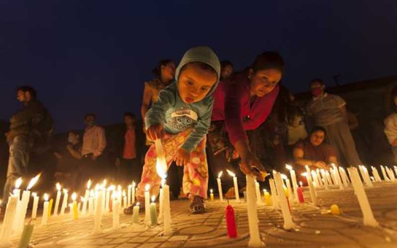 Varias personas encienden velas durante una ceremonia celebrada frente a las ruinas de la célebre torre de Dharahara en memoria de las víctimas del terremoto del 25 de abril, en Katmandú, Nepal.