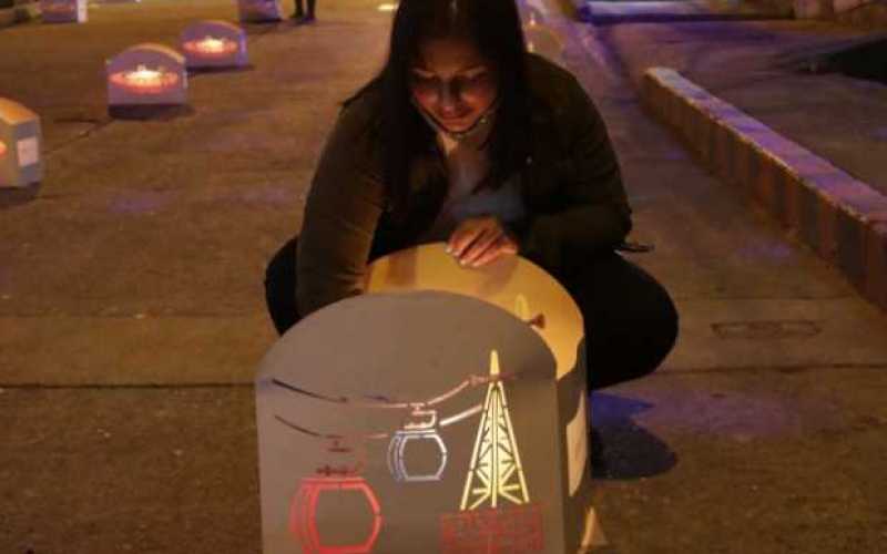 Tatiana Velásquez enciende la vela de uno de los mil 100 faroles que elaboraron la Fundación Comunitaria Huellas de Vida en conj